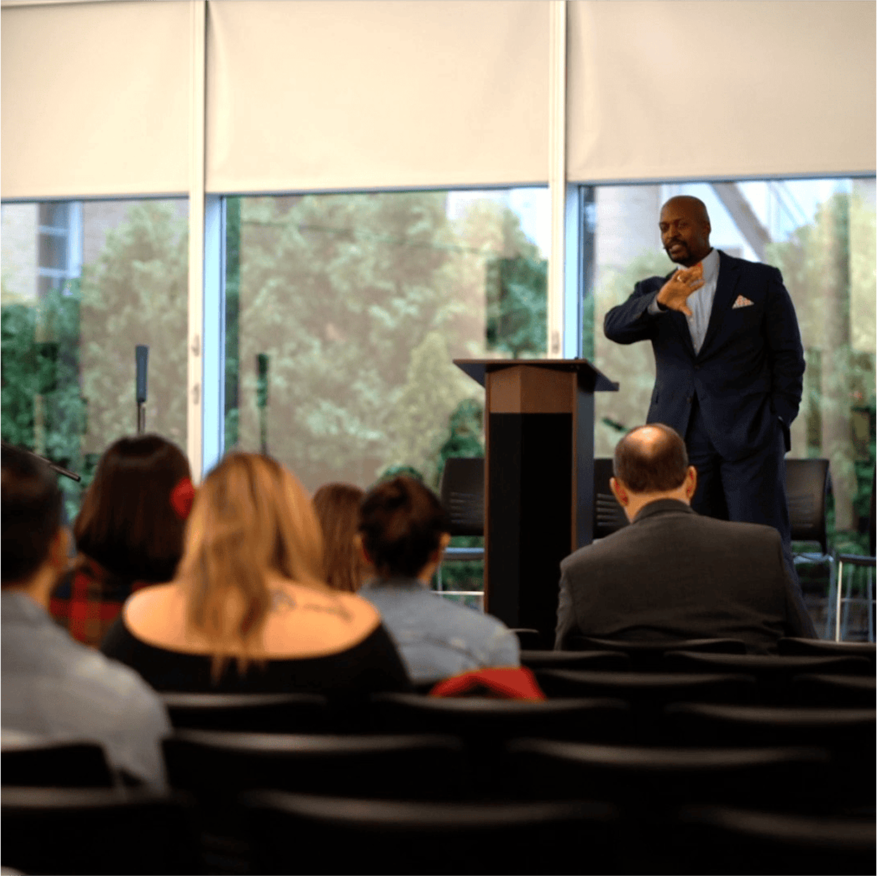 Speaker presenting to an audience at an indoor event near a podium