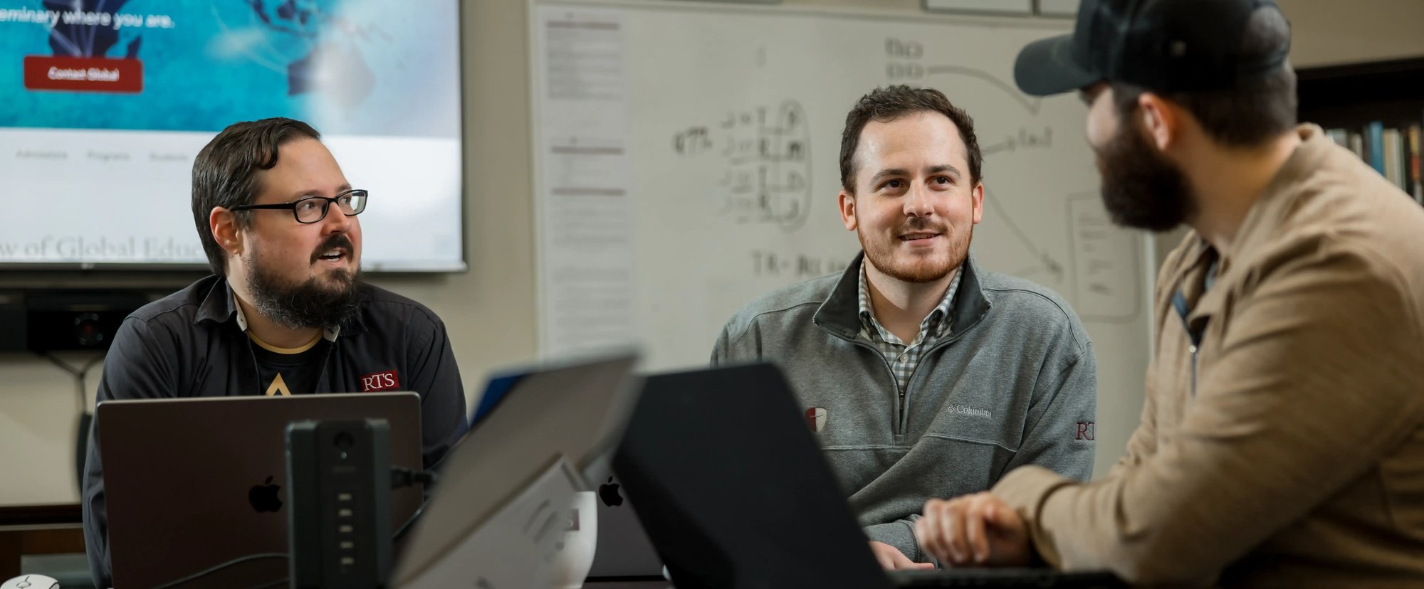 Students collaborating in a classroom at the Charlotte campus while working on laptops