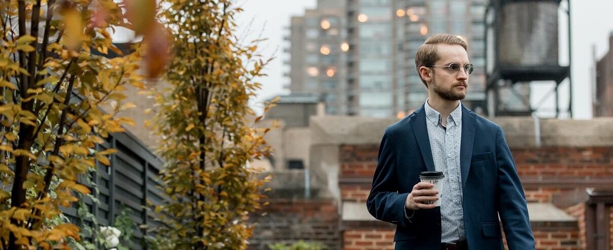 Man walking outdoors in the city while holding a cup of coffee