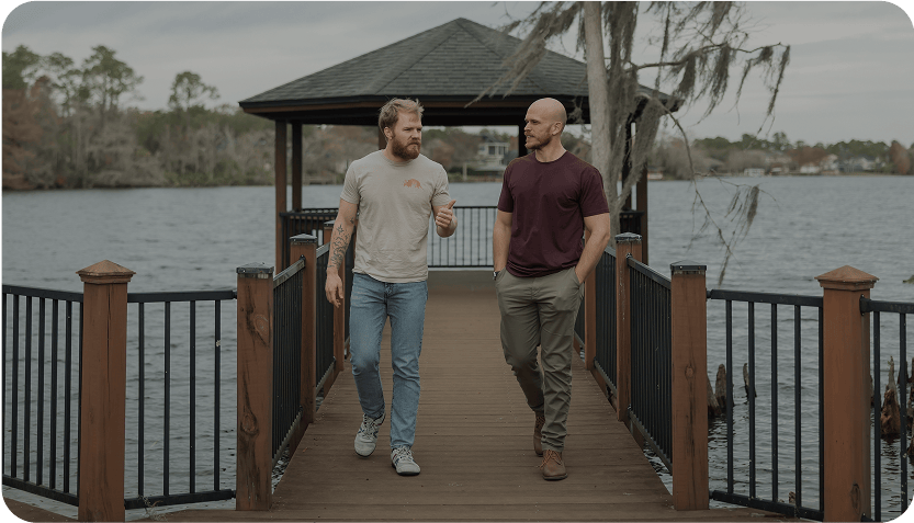 Two men walking and talking on a campus dock.