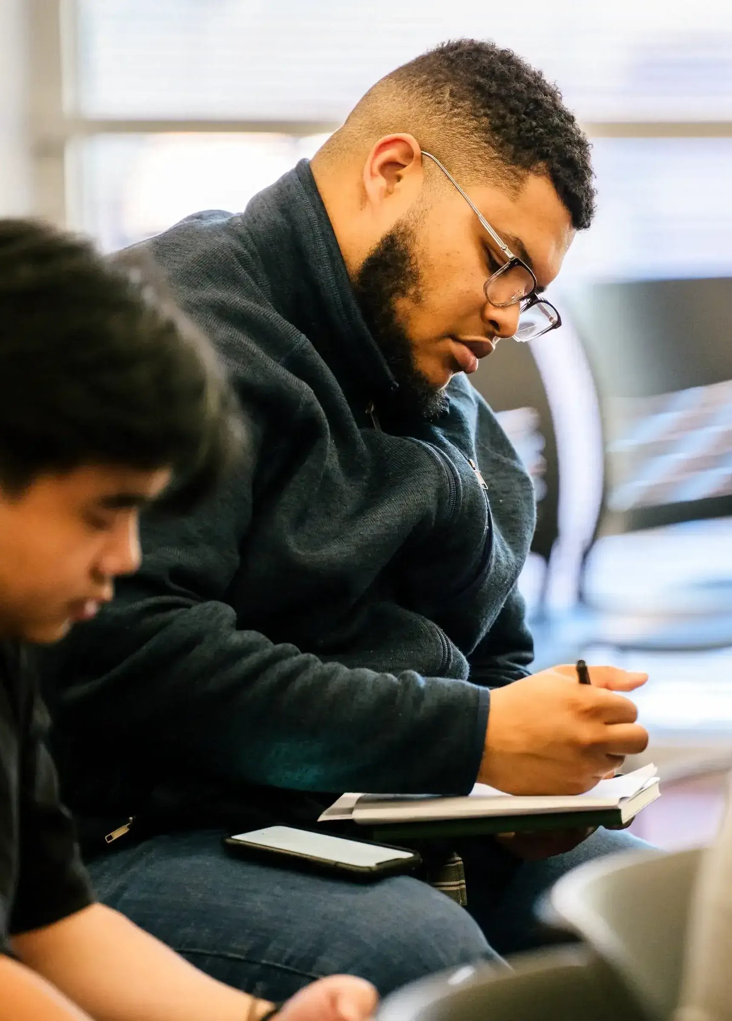 Close-up of a student taking notes during a classroom lesson in a seminary setting